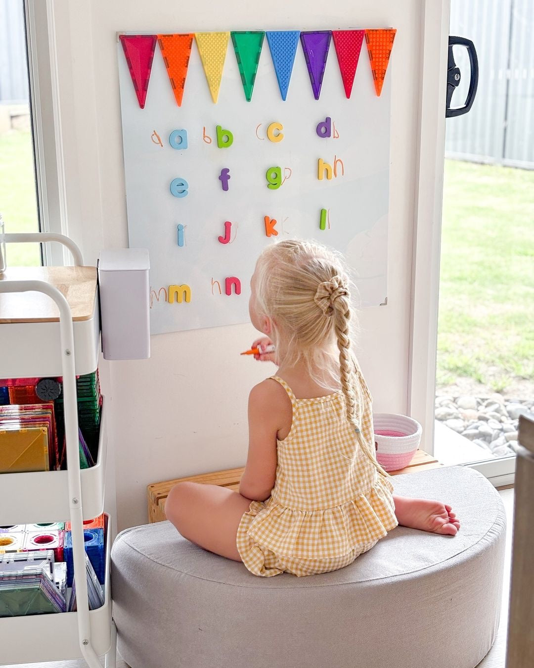 toddler learning abcs using Curious Columbus foam alphabet fridge magnets on a vertical white board